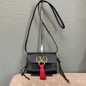 Preloved Sleek Black Crossbody Bag with Gold Emblem and Red Tassel